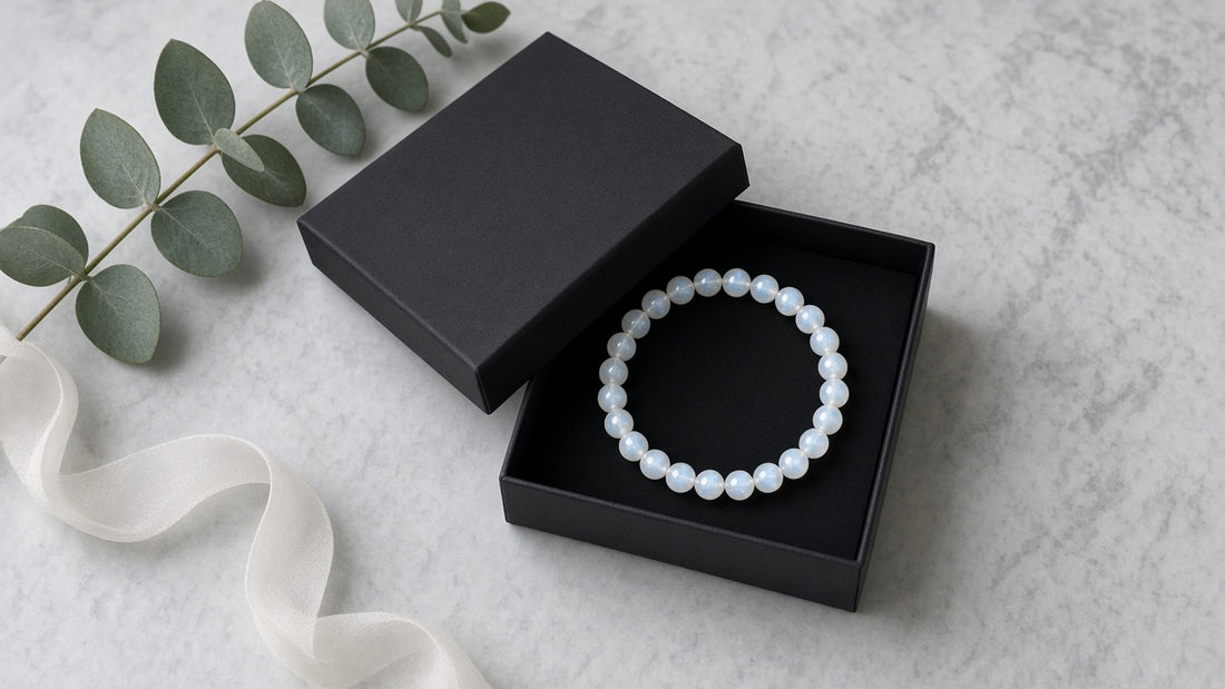 Armband aus Mondsteinperlen in einer schwarzen Geschenkschachtel auf hellem Marmor