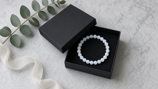 Armband aus Mondsteinperlen in einer schwarzen Geschenkschachtel auf hellem Marmor